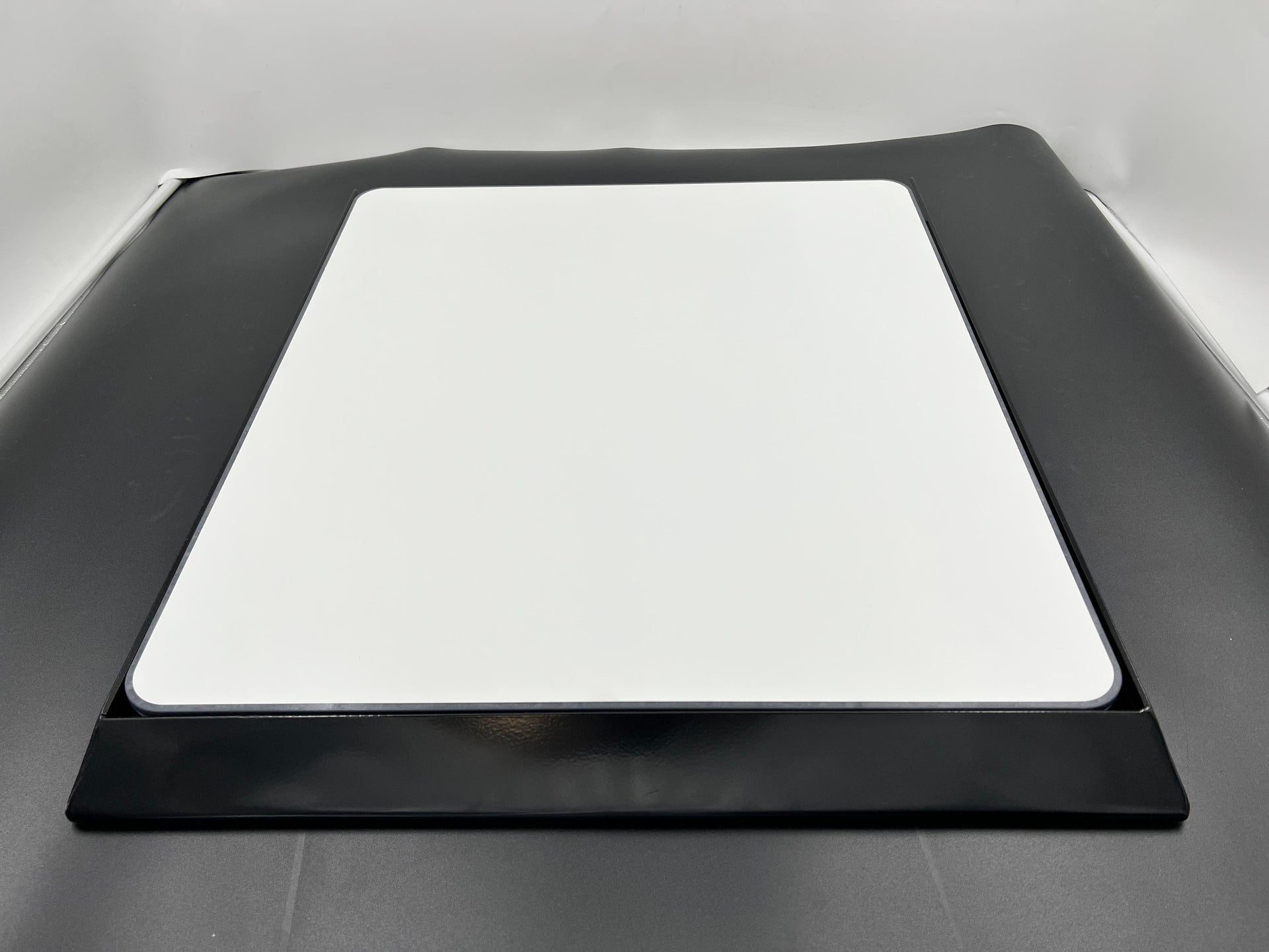 Black car hood with a white square patch on a gray background